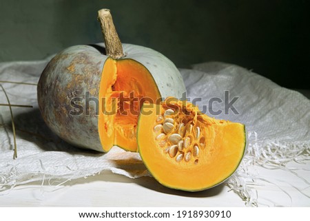 Still life of sliced pumpkin on plastic sack indoor. Ripe pumpkin and slice of pumpkin with seeds.