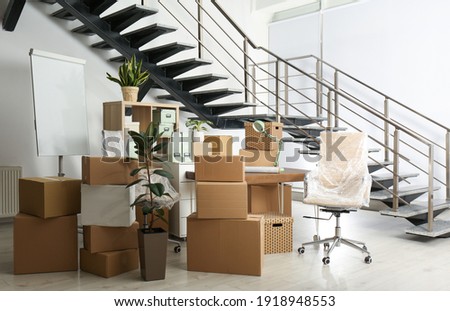 Cardboard boxes and furniture near stairs in office. Moving day Royalty-Free Stock Photo #1918948553