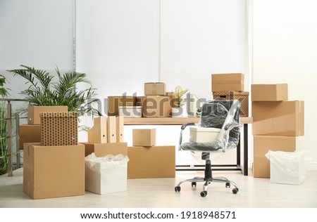 Cardboard boxes and packed chair in office. Moving day Royalty-Free Stock Photo #1918948571