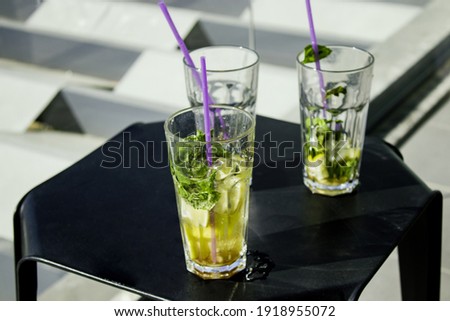 Concept: Vacantion during the pandemy.
Three glasses with mojito on a black little table at a hotel's balcony. Two of glasses are almost empty and one of them left a watermark on the table. Each of th