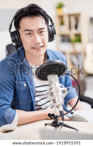 asian man with headphones and microphone recording podcast at studio 