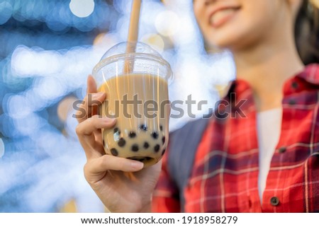 close up of smiling asian woman holds a cup of tapioca ball tea at city night while on vacation Royalty-Free Stock Photo #1918958279