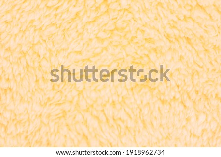 Background picture of a soft fur orange carpet. wool sheep fleece closeup texture background. Fake color beige fur fabric. top view.