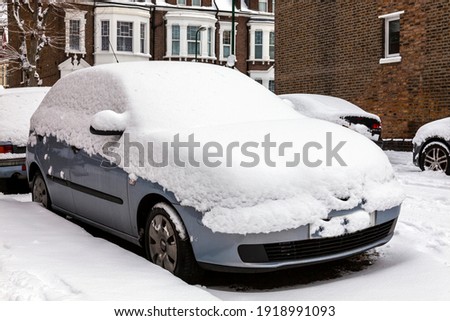 Street winter cityscape with snow covered frozen cars after a blizzard snowfall in London England UK, stock photo image