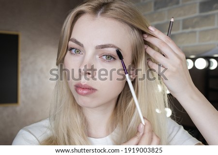 Close-up of a young woman wearing makeup in front of a mirror