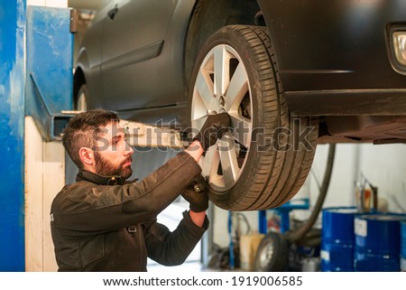 Mechanic performs tire change on the car in the workshop Royalty-Free Stock Photo #1919006585
