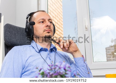 Podcast concept - happy adult man audio blogger in headphones with laptop computer and microphone broadcasting at home office. attractive man with headphones and laptop talking on mic, online radio.