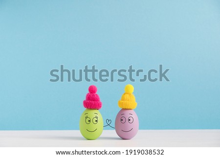 Easter holiday concept with cute eggs with funny faces. Different emotions and feelings. Lovely couple in hats holding hands.