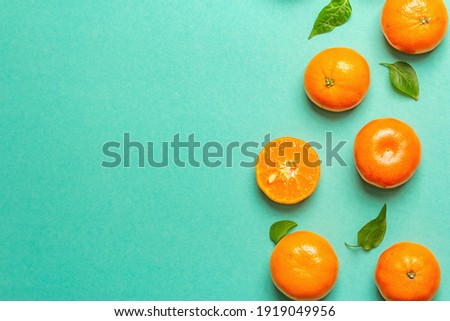 Ripe juicy tangerines and fresh leaves. Sunny summer turquoise background, top view