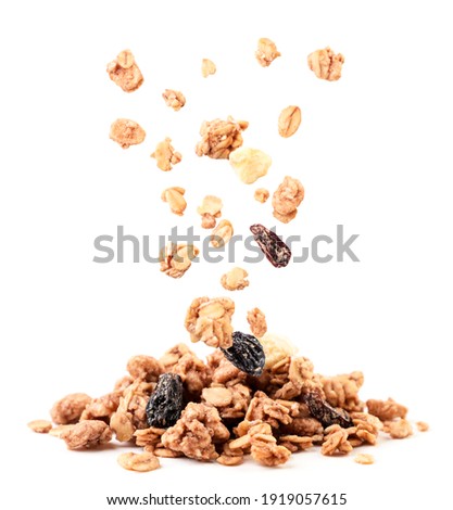 Crispy granola with raisins and banana falling on a heap close-up on a white background. Isolated Royalty-Free Stock Photo #1919057615