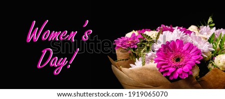 Large beautiful bouquet of chrysanthemums, gerberas, roses and ferns in pink and purple colors, packed in brown craft paper and isolated on a black background. Postcard for the holiday. Close-up.