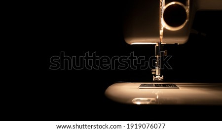 Light from bulb of modern sewing machine in darkness, front view. banner with copy space