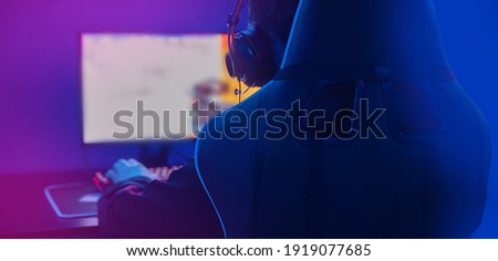 Background professional gamer playing tournaments online games computer with headphones, red and blue. Royalty-Free Stock Photo #1919077685