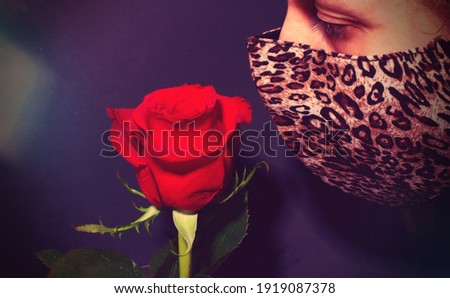 shot of a beautiful woman wearing a fashioned surgical mask while smelling a rose