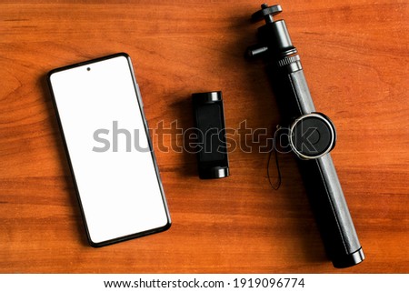Monopod and smartphone with blank screen. Blogging supplies mockup.