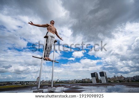 Man standing on the rooftop with dramatic clouds and cityscape on background. Concept of confidence, bravery and individuality. Royalty-Free Stock Photo #1919098925