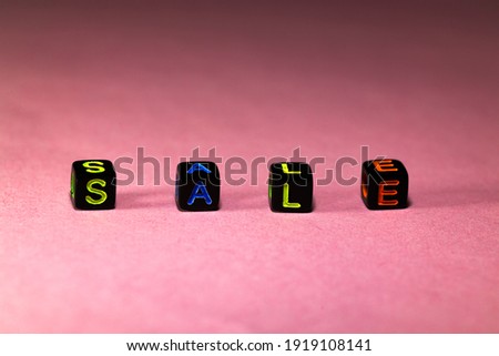 inscription sale of plastic black blocks on a pink background for an advertising banner with a discount. Business concept. Close-up. Selective focus.