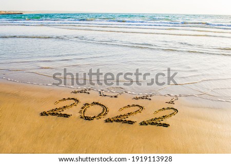Happy New Year 2022 text on the sea beach. Abstract background photo of coming New Year 2022 and leaving year of 2021 Royalty-Free Stock Photo #1919113928