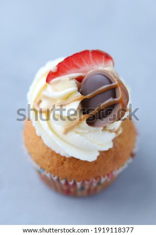 Caramel cupcake with strawberries on a gray background. Copy space. Delicious dessert. Top view. Vertical image