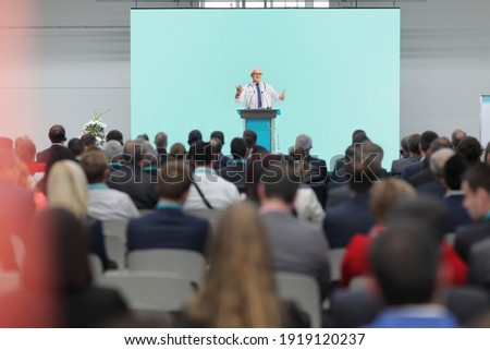 Mature doctor giving a speech on a stage at a conference in front of an audience Royalty-Free Stock Photo #1919120237