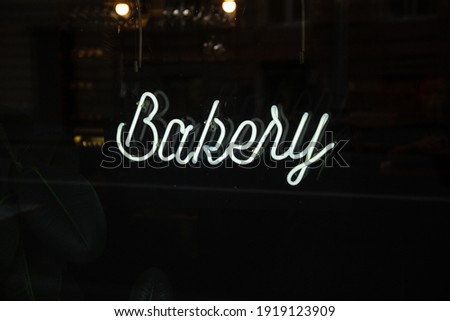 White neon sign of bakery with black background . 