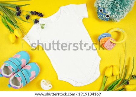 Springtime baby apparel flatlay on bright yellow table with colorful accessories. Mock up with negative copy space for your text or design here. Royalty-Free Stock Photo #1919134169