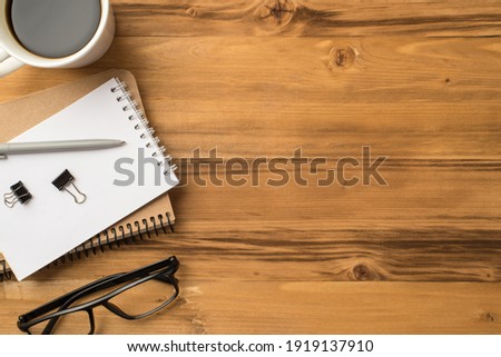 Above overhead close up flat lay view photo of mug of beverage stack of craft notepads eyeglasses isolated loft brown backdrop