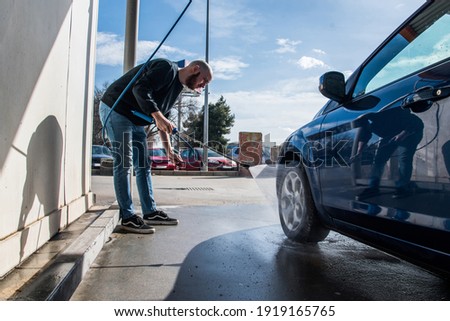 Car washing concept. Man using high pressure water to clean a tire of his car