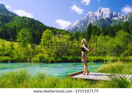 People in nature. Tourist woman with raised arms up in green nature background. View on Zelenci (into English means - green) natural reserve in Slovenia, Europe. Travel, Freedom, Lifestyle concept.