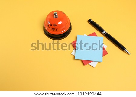 Stacked  paper notes with pen and service bell on the yellow background 