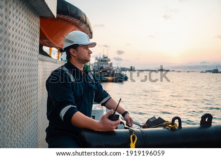 Marine Deck Officer or Chief mate on deck of offshore vessel or ship , wearing PPE personal protective equipment - helmet, coverall. Ship is on background Royalty-Free Stock Photo #1919196059