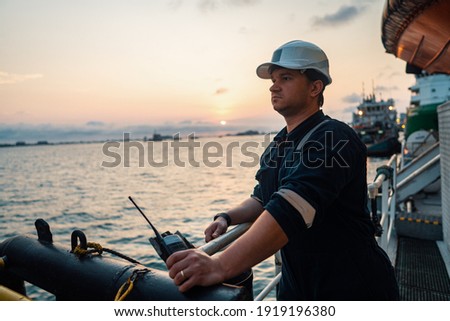 Marine Deck Officer or Chief mate on deck of offshore vessel or ship , wearing PPE personal protective equipment - helmet, coverall. Ship is on background Royalty-Free Stock Photo #1919196380