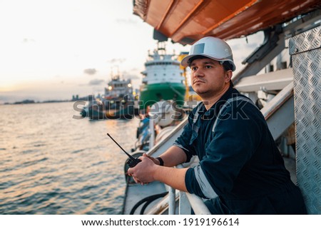Marine Deck Officer or Chief mate on deck of offshore vessel or ship , wearing PPE personal protective equipment - helmet, coverall. Ship is on background Royalty-Free Stock Photo #1919196614