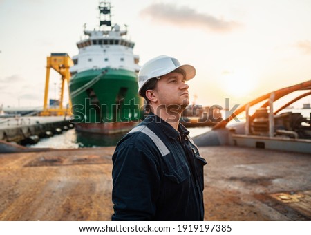 Marine Deck Officer or Chief mate on deck of offshore vessel or ship , wearing PPE personal protective equipment - helmet, coverall. Ship is on background Royalty-Free Stock Photo #1919197385