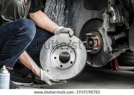 Brand new brake discs for garage cars. Auto mechanic,in process of new tire replacement, Car brake repairing in garage	 Royalty-Free Stock Photo #1919198783
