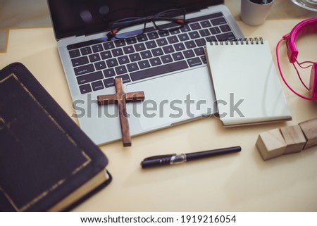Cross on bible with headset and laptop in online study bible concept. Royalty-Free Stock Photo #1919216054
