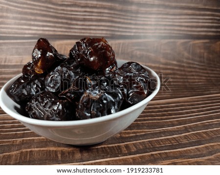 Selective focus.Dried sweet dates on bowl on wooden table background. Healthy food concept.Shot were noise and film grain.