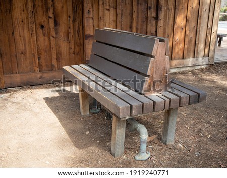 Double sided wooden park bench placed on top of pipes to cover up.
