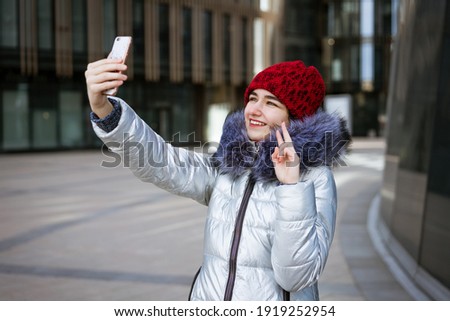 young woman in a warm jacket communicates online by phone on the street