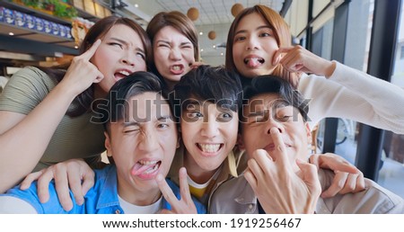 asian young six friends taking selfie and making funny face in restaurant happily