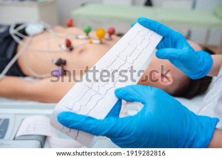 Heart cardiogram in the hands of a doctor close-up. Cardiologist is studying the testimony of an electrocardiograph. Royalty-Free Stock Photo #1919282816