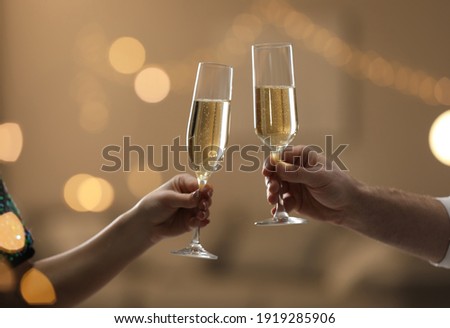People clinking glasses of champagne against blurred background, closeup. Bokeh effect Royalty-Free Stock Photo #1919285906