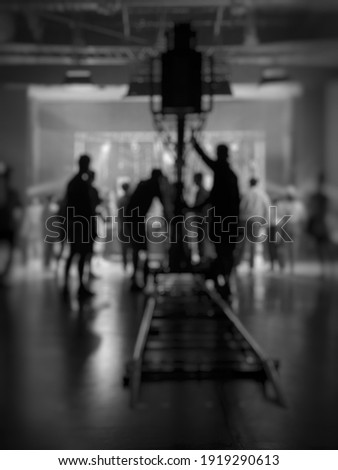 Blurred behind the scenes of music video shooting production crew team silhouette and camera equipment in studio. Soft focus. Black and White.