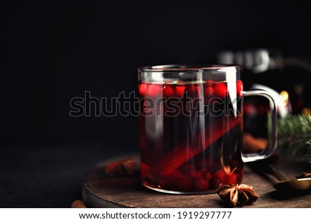 Tasty hot cranberry tea with anise and cinnamon on black table. Space for text