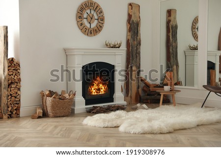 Beautiful fireplace and basket with firewood in contemporary room interior