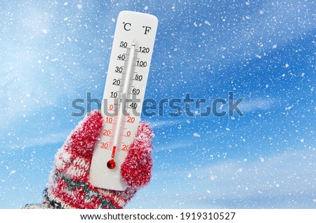 White celsius and fahrenheit scale thermometer in hand. Ambient temperature minus 27 degrees celsius Royalty-Free Stock Photo #1919310527