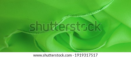 Green silk organza with wavy piping. Border around the edge of the fabric. Abstract background. texture pattern. Silk organza has a delicate open weave. Wave background. Copy space