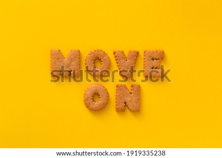 Word Move on in the middle of the picture made of tasty crunchy cookies in the form of English alphabet letters, textured bright yellow background, health, dieting and medical concept. Copy space