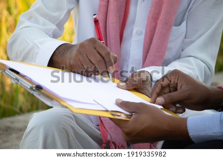 Selective focus on farmer hands, Close up of farmer hands signing on documents while sitting near the farmland - concept of cotract farming, business deal and farm loan approval