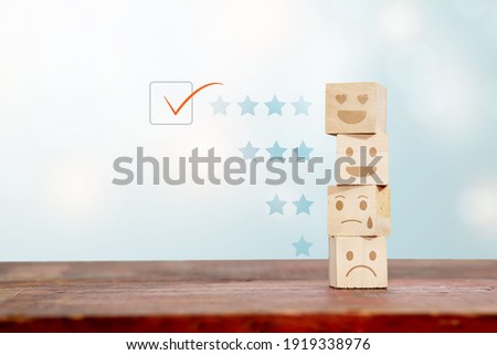 A wooden block satisfaction concept with a satisfied icon and a star sorted in stages. With a light blue background